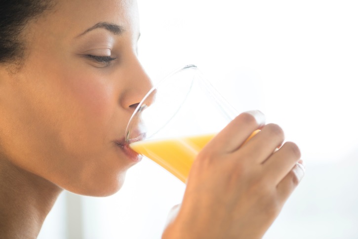 Close-Up Of Woman Drinking Orange Juice